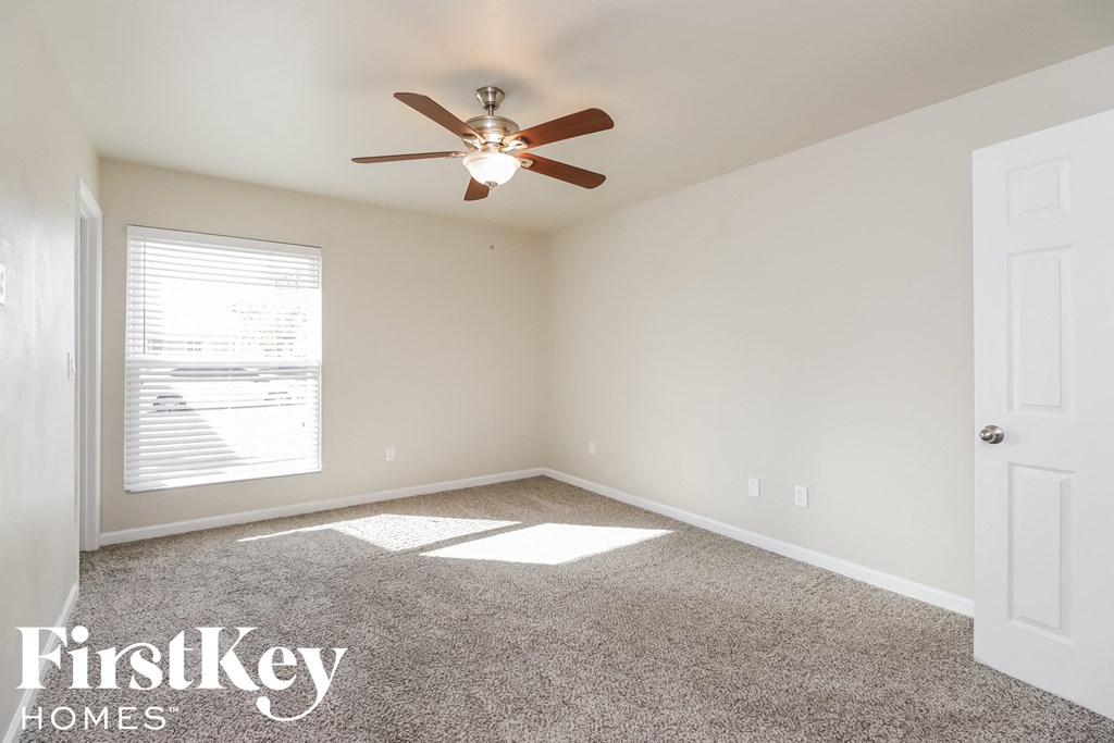 an empty room with a ceiling fan and a window