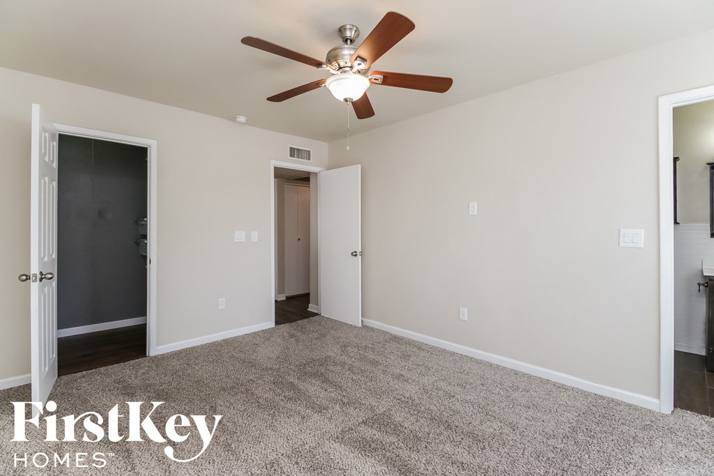 a empty living room with a ceiling fan and a door to a closet