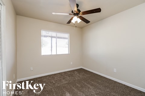 the spacious living room with ceiling fan and carpet
