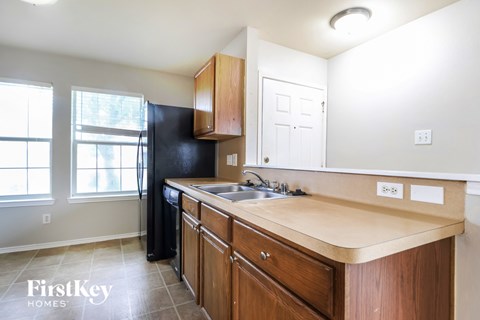 A kitchen with wooden cabinets and a black fridge.