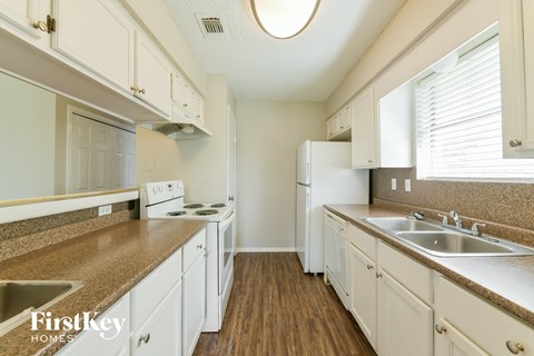 a kitchen with white cabinets and white appliances and a counter top