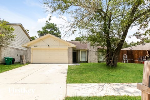 a white house with a driveway and a tree