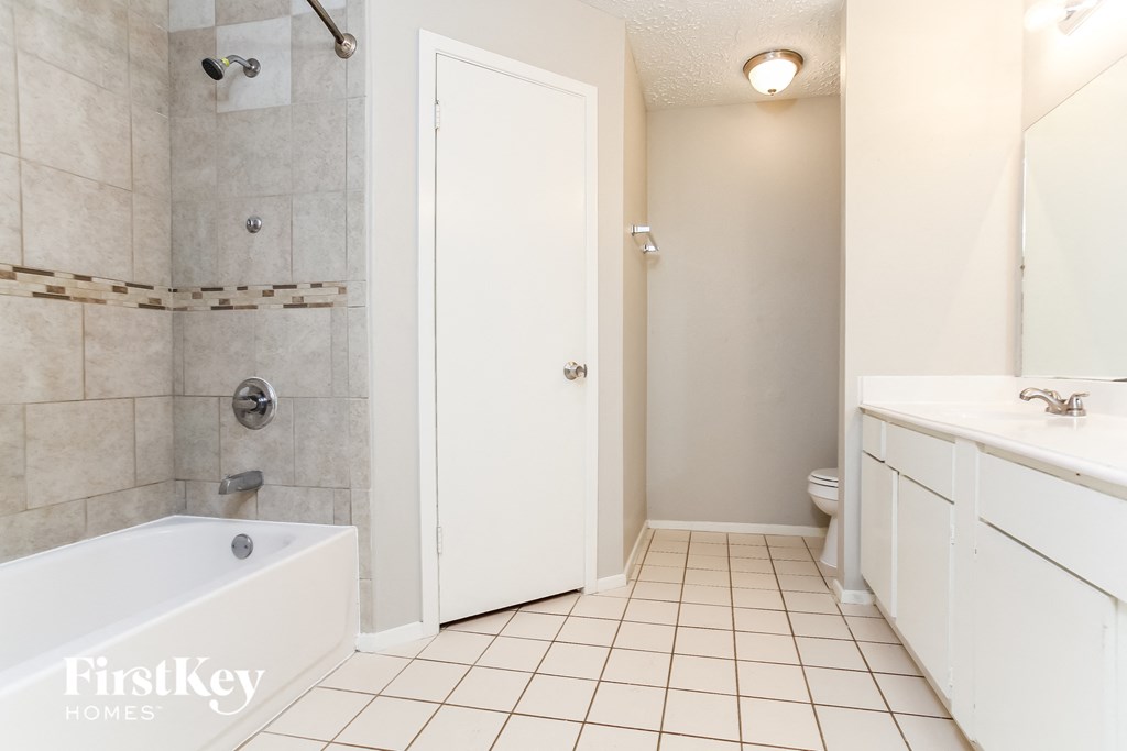 a white bathroom with a tub and a sink and a toilet
