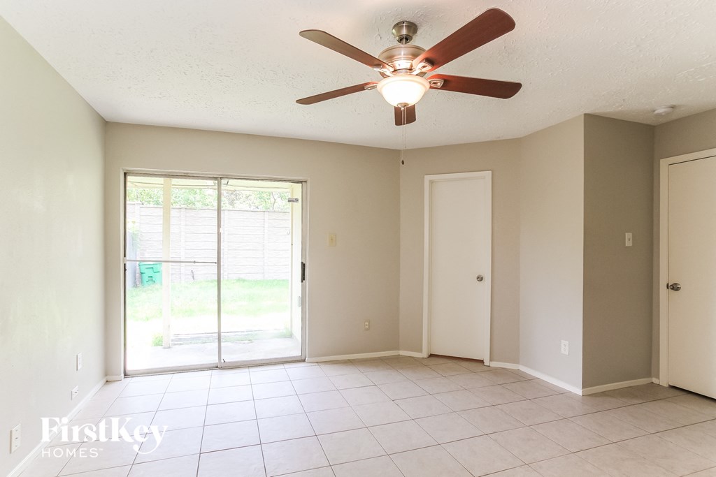 an empty living room with a ceiling fan and a sliding glass door