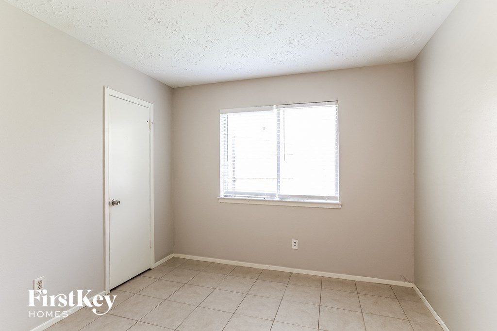 a bedroom with a window and a tiled floor
