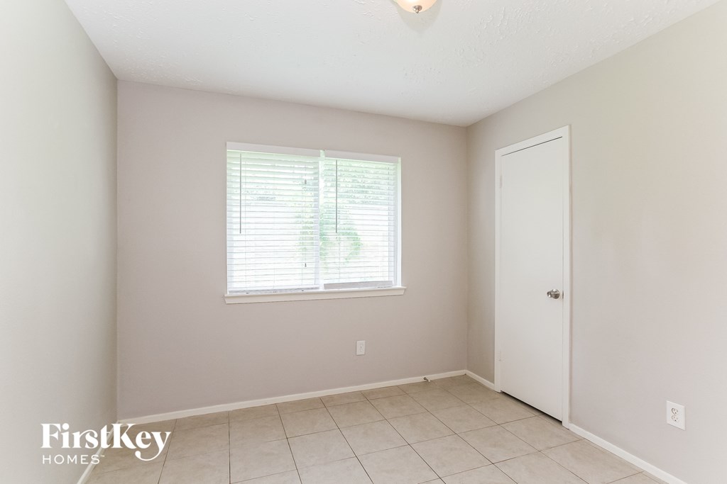 a bedroom with a large window and a tiled floor