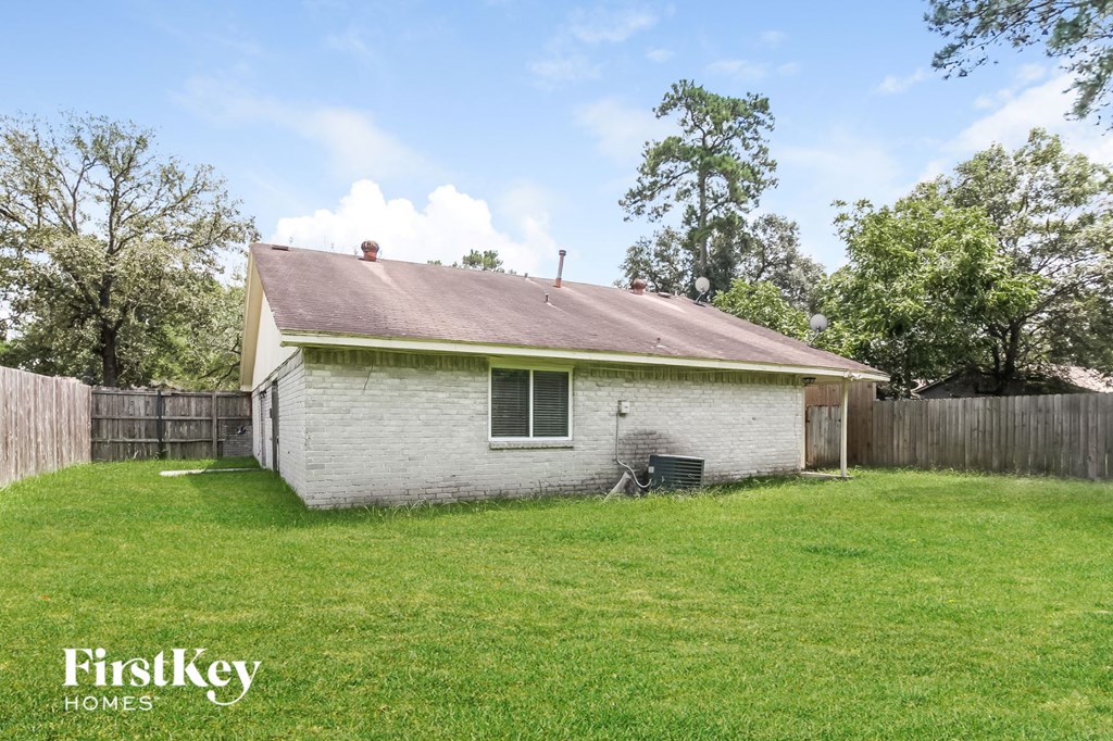 a small white house in a backyard with a lawn and a fence