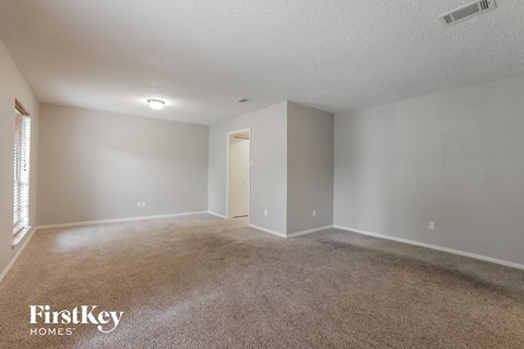 a spacious living room with carpet and a door to a closet