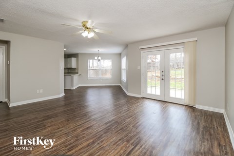 A spacious room with wooden floors and a ceiling fan.