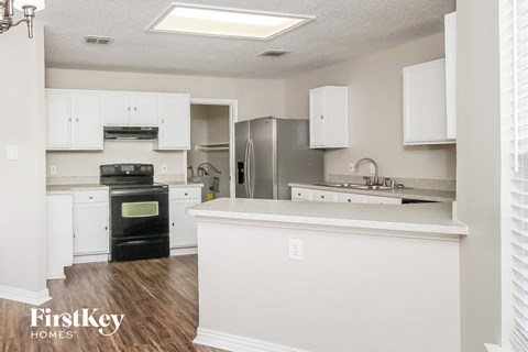 A kitchen with white cabinets and a black oven.