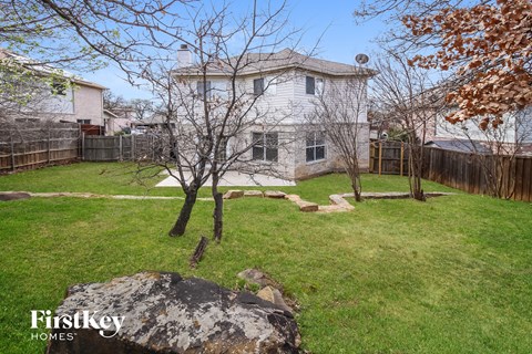 A large rock sits in the middle of a grassy yard.