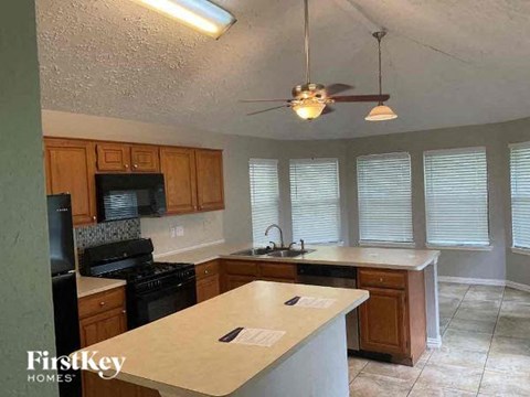 A kitchen with a black stove top oven and wooden cabinets.