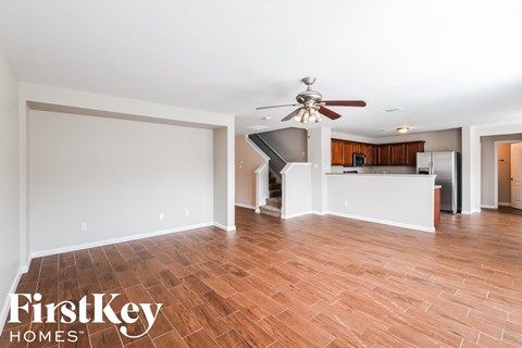 A spacious room with wooden flooring and a ceiling fan.
