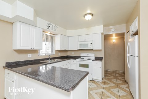 a kitchen with white cabinets and granite counter tops and white appliances