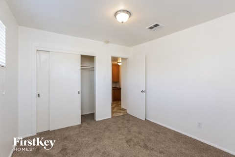 a bedroom with white walls and carpet and a door to a bathroom