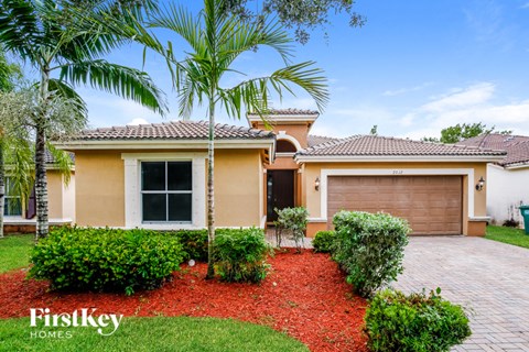 a home with a garage and palm trees in front of it