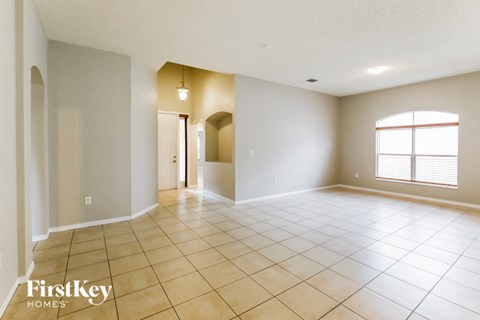 an empty living room with tiled floors and a large window