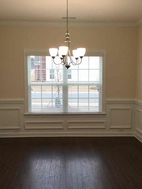 an empty living room with a window and a chandelier