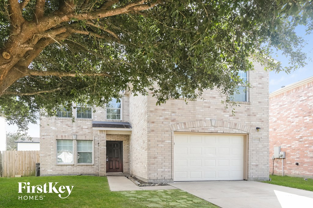 a white brick house with a garage door and a tree