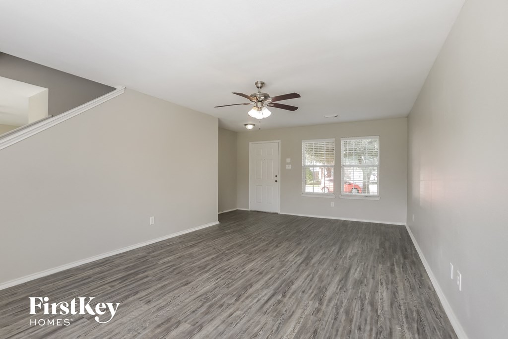 the living room of an empty house with a ceiling fan
