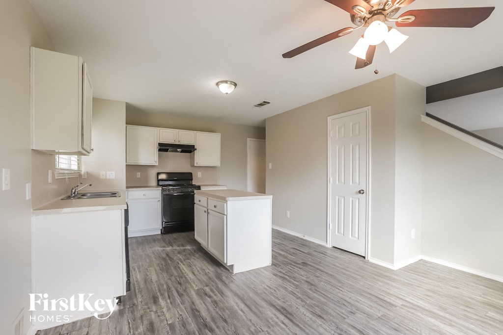 a kitchen with white cabinets and a ceiling fan