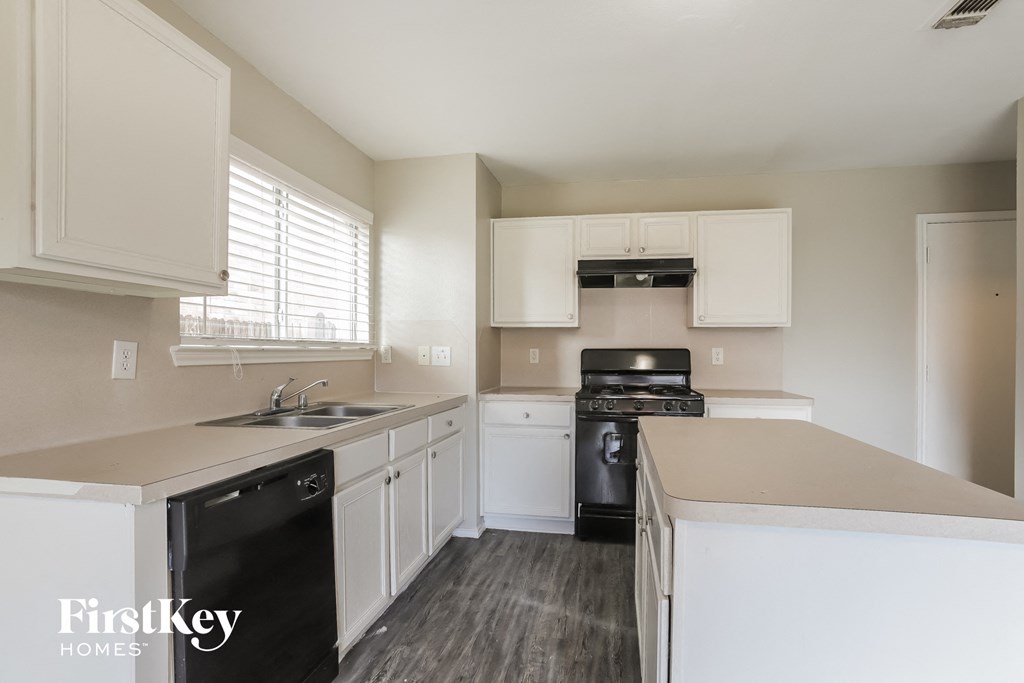 a kitchen with white cabinets and black appliances and a sink