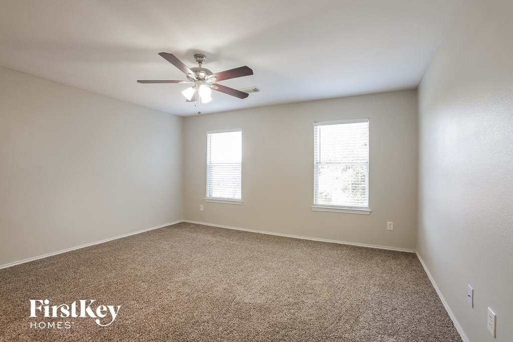 an empty room with a ceiling fan and two windows