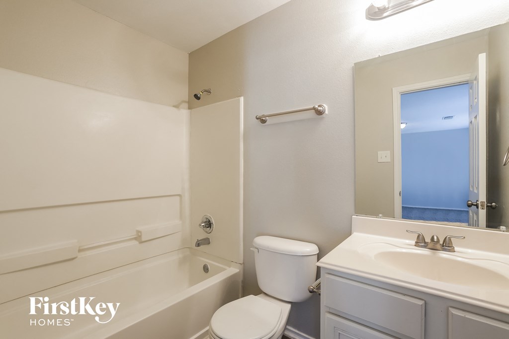 a bathroom with a toilet sink and tub and a mirror