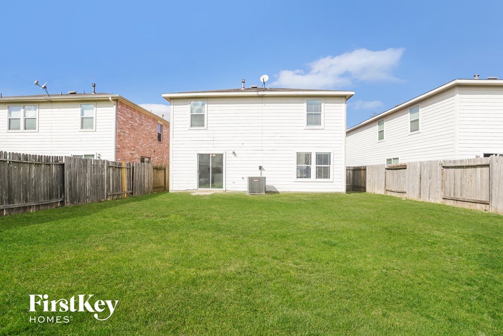 the backyard of a white house with a yard and a wooden fence