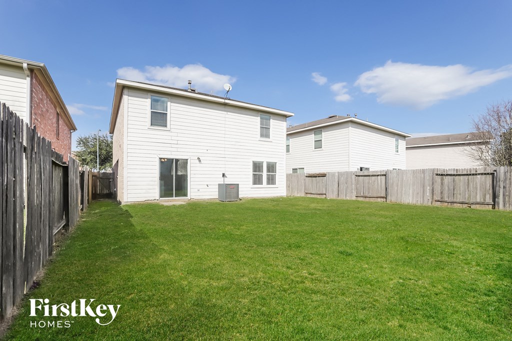 the backyard of a white house with a yard and a wooden fence