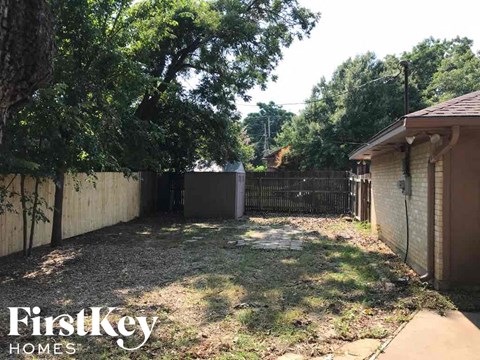 a backyard with a fence and a yard with grass and trees