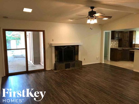 an empty living room with a fireplace and a ceiling fan
