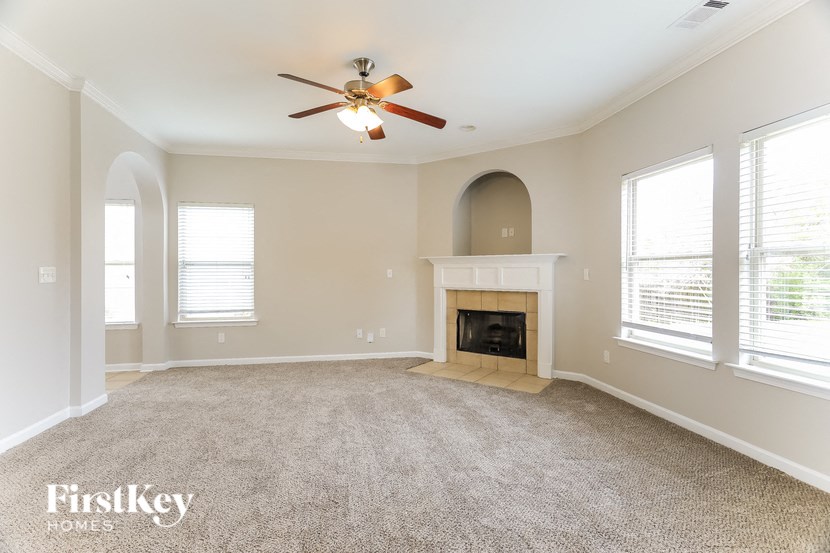 an empty living room with a fireplace and a ceiling fan