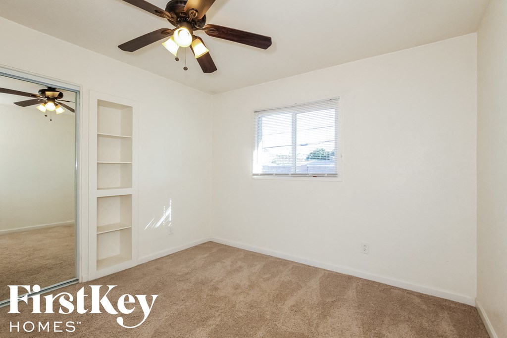 an empty room with a ceiling fan and a window
