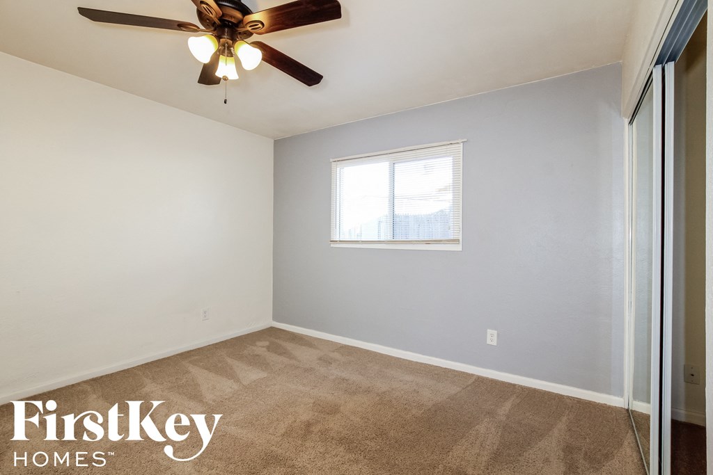 an empty room with a ceiling fan and a window