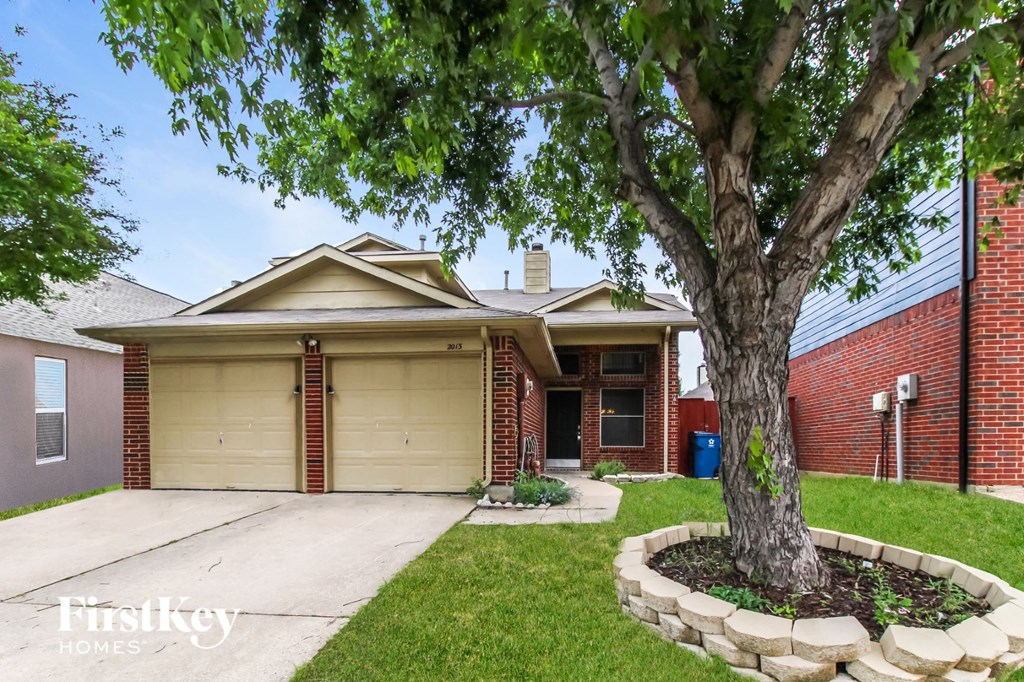 a home with a tree in the front yard and a driveway