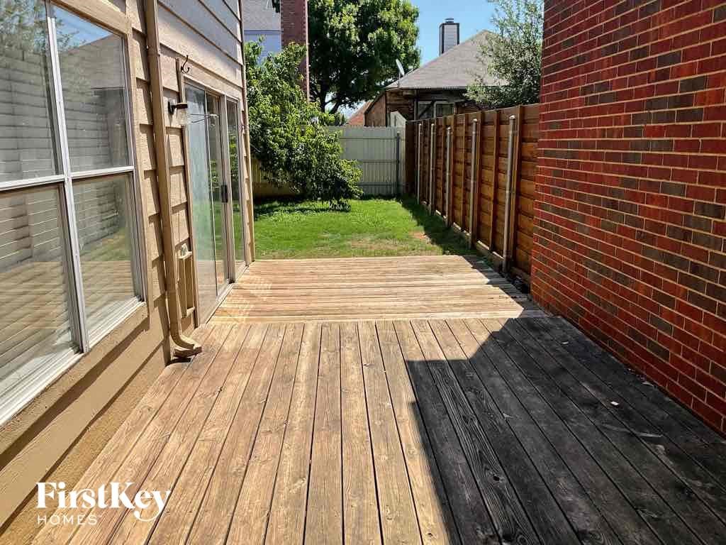a backyard with a wooden deck and a brick fence
