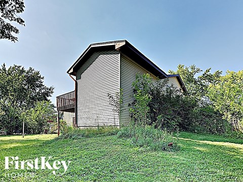 a small wooden barn with a deck on a grass field