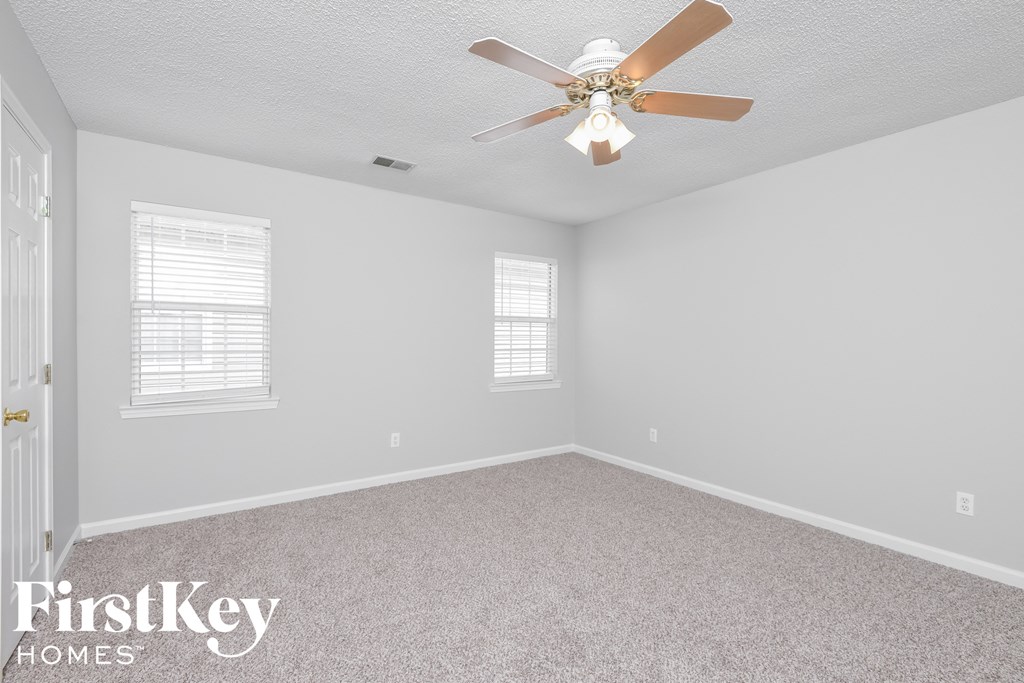 a bedroom with white carpet and a ceiling fan