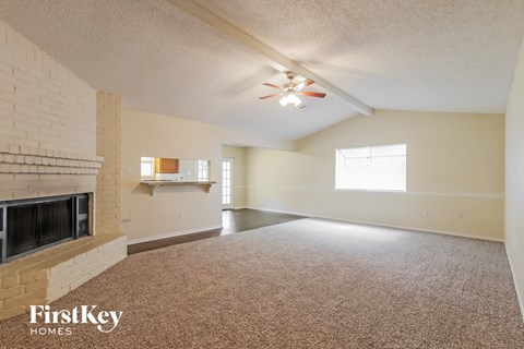 an empty living room with a fireplace and a ceiling fan