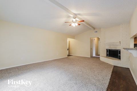 an empty living room with a fireplace and a ceiling fan