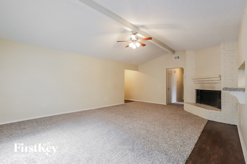 an empty living room with a fireplace and a ceiling fan