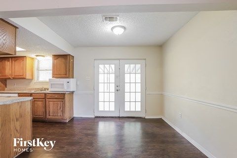 a kitchen with white walls and wooden cabinets and a white door