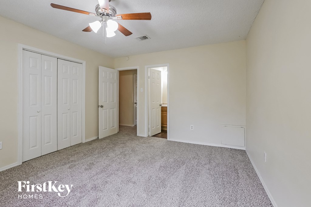 the living room of an empty house with white doors and a ceiling fan