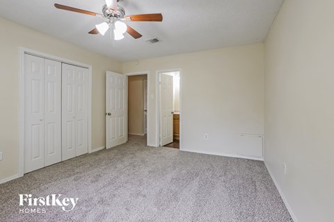 the living room of an empty house with white doors and a ceiling fan