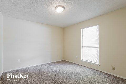 a bedroom with a large window and a carpeted floor