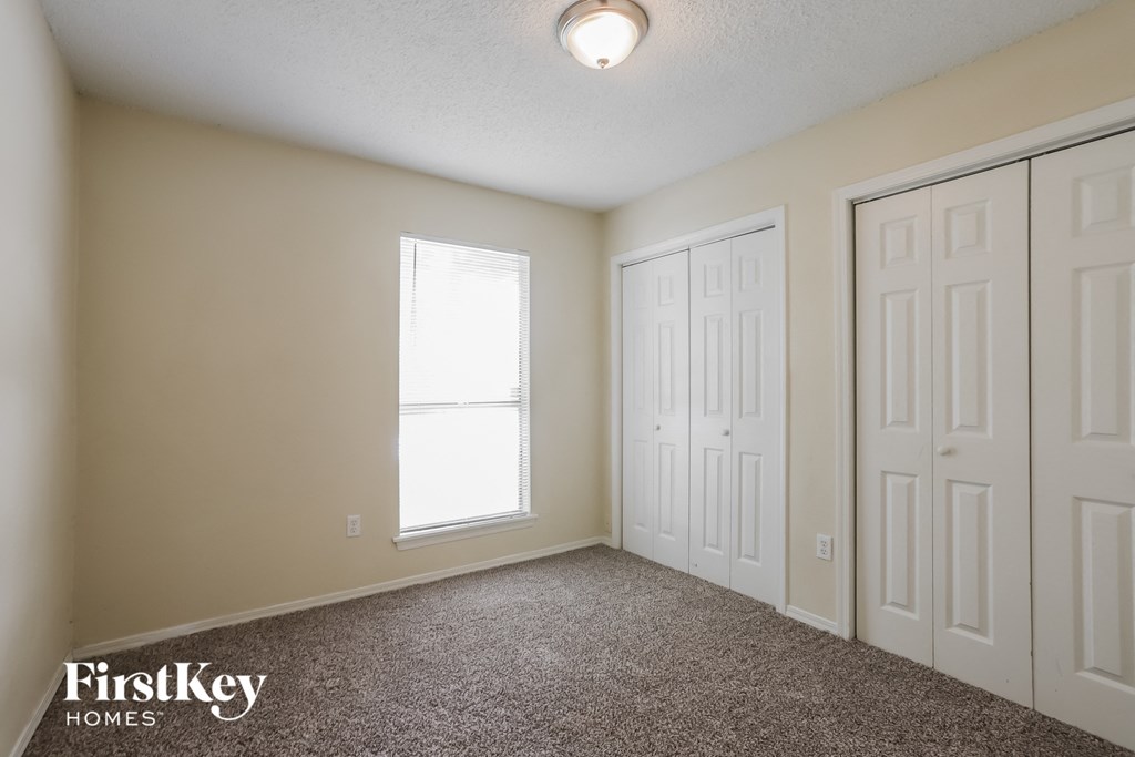 a bedroom with two closets and two doors and a window