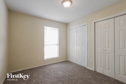 a bedroom with two closets and two doors and a window