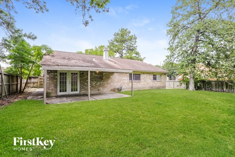 a backyard with a brick house and a green lawn