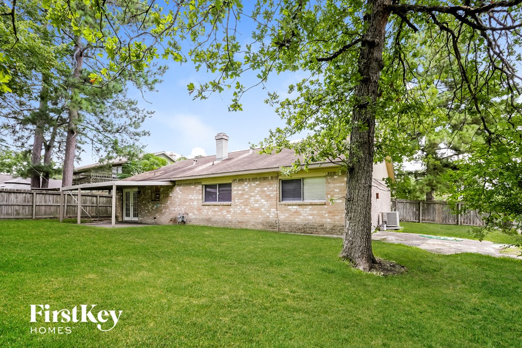 a backyard with a brick house and a tree